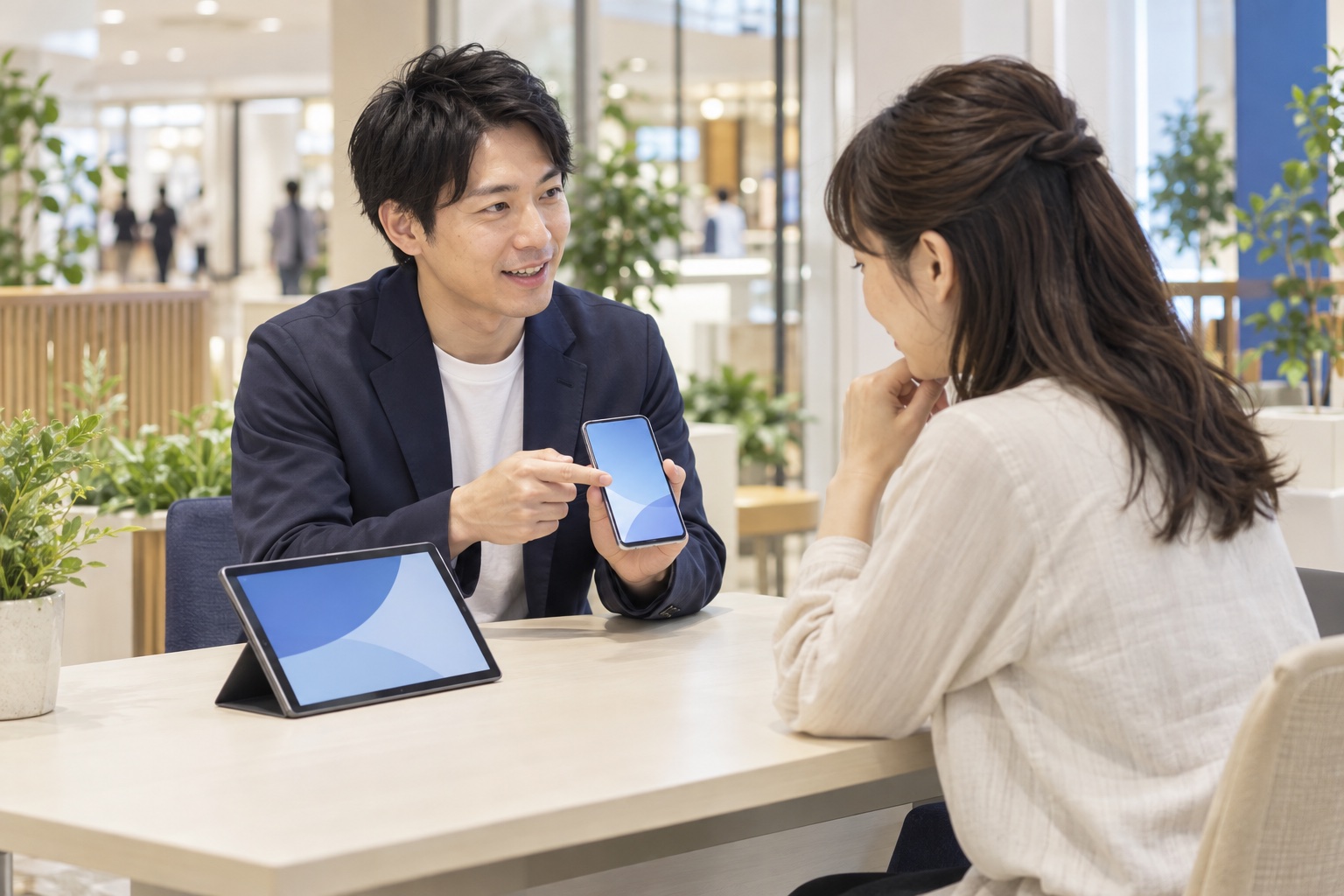 スマートフォンとタブレットを使い、お客様に通信サービスを案内するイメージ